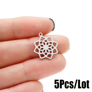 Macro shot of a 5Pcs silver stainless steel mandala flower pendant held by fingers