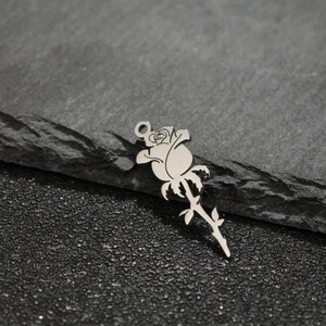 Close-up of 18k gold plated stainless steel rose flower pendant on a textured stone surface