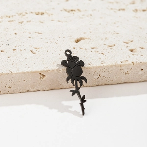 Detail shot of matte black rose flower pendant on natural beige stone background