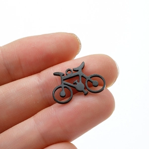 Miniature black stainless steel bicycle pendant shown against a finger for scale