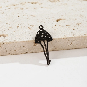 Artistic black mushroom charm with cutouts and leg details on a textured stone base