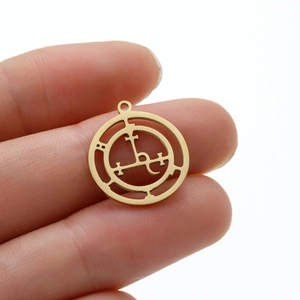 Détail d'un pendentif rond doré évidé avec des symboles occultes géométriques pour femme