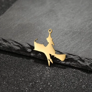 Polished gold stainless steel witch broom pendant on dark stone background close-up