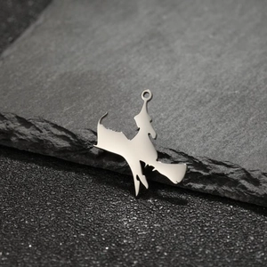 Macro detail of witch on broom stainless steel pendant on a dark natural stone background