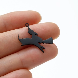 Close-up of a small black stainless steel witch on a broom pendant for Halloween jewelry