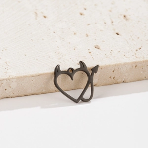 Macro shot of matte black devil heart pendant with horns and arrow tail on stone