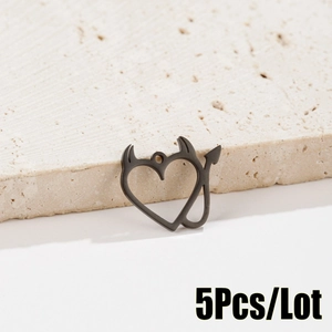 Detailed macro view of five matte black devil heart pendants on a textured stone surface