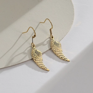 Polished gold angel wing earrings with intricate hollow carved feather texture on a pedestal