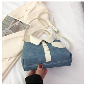 Detail van creatieve blauwe denim tas met wit hemdkraagontwerp en slanke lederen riem