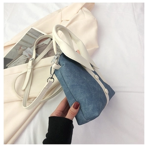 Detail van blauwe denim emmertas met witte lederen bekleding en decoratieve knopen