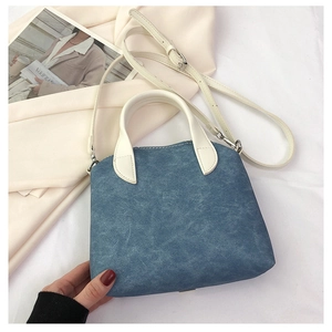 Detail van lichtblauwe denim handtas met witte riem op een lifestyle achtergrondfoto