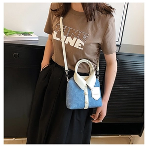 Close-up of blue denim shirt-style handbag with white leather collar and button details