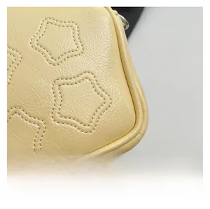 Close-up of yellow leather crossbody bag showing star stitching and refined edge details