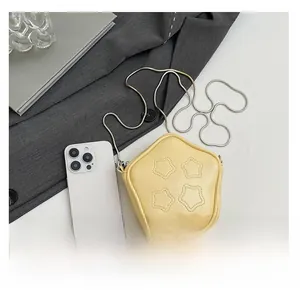 Detail view of mini yellow star-shaped PU bag with silver chain next to a phone