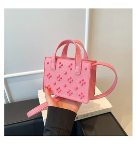Détail d'un mini sac rose clouté en cuir grainé avec finitions rivets métalliques