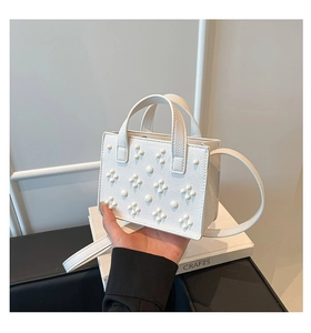 Détail du sac boîte blanc à motif litchi avec perles florales et doubles poignées