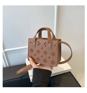 Détail d'un mini sac cabas marron en cuir avec rivets décoratifs et bandoulière