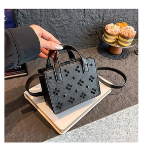 Détail du sac à bandoulière en cuir noir avec motif floral en rivets et style vintage