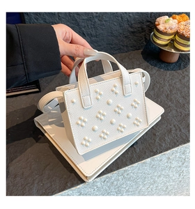 Gros plan d'un mini sac cabas blanc en cuir grainé avec des détails floraux cloutés