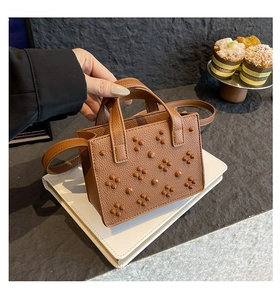 Détail du mini sac cabas marron foncé avec rivets floraux argentés et poignée
