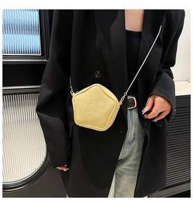 Detail of bright yellow star-shaped crossbody bag with quilted pattern and chain strap