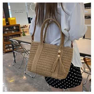 Detail van strooien tas met ingewikkelde holle weeftextuur en kwastje met houten kralen