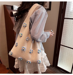 Détail du sac cabas en tricot avec des textures florales et des motifs au crochet beige