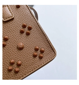 Gros plan d'un sac en cuir marron grainé avec des détails de clous pyramidaux chic