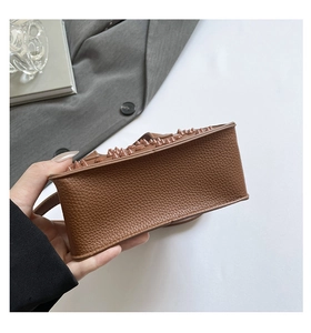 Détail du sac en cuir marron texturé avec des rangées de rivets assortis sur le bord inférieur
