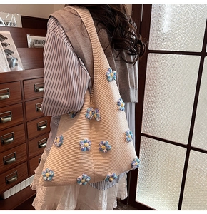 Gros plan du sac à bandoulière en tricot beige avec des fleurs au crochet 3D colorées