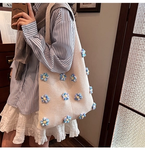 Gros plan d'un sac cabas en maille avec des appliqués floraux au crochet bleu et jaune