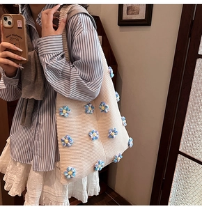 Gros plan du sac en tricot crème avec détails de fleurs au crochet bleues et jaunes
