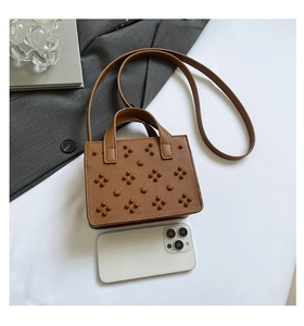 Mini sac à bandoulière marron clouté présenté à côté d'un smartphone pour la taille