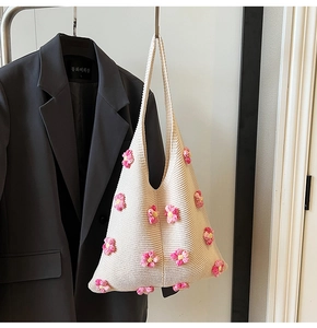 Détail d'un sac à bandoulière en maille avec fleurs 3D sur un cintre en bois