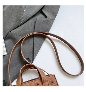 Vue de dessus d'un sac en cuir marron à motif litchi avec poignées et bandoulière