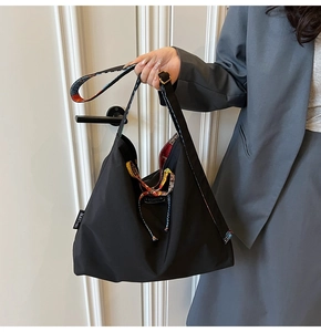 Detail of black nylon tote bag featuring contrast geometric strap and MAYI 1983 brand tag