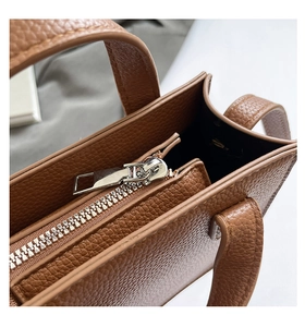 Détail du sac en cuir marron grainé avec fermeture éclair en métal argenté et poignée