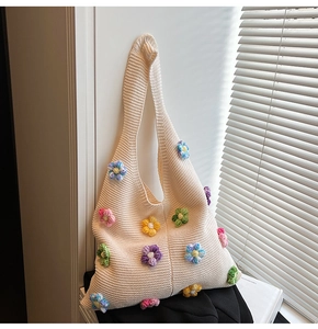 Nahaufnahme cremefarbene Stricktasche mit bunten 3D-Häkelblumen und weicher Textur