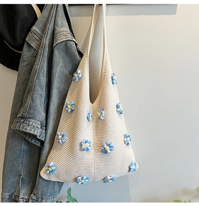 Gros plan d'un sac bandoulière en tricot crème avec détails de fleurs 3D colorées