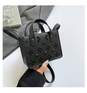 Détail du mini sac cabas noir en cuir grainé avec des rivets en forme de cœur