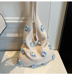 Détail du sac à bandoulière en tricot crème avec fleurs 3D bleues et jaunes au crochet