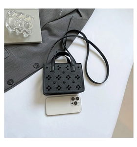 Détail du mini sac noir à rivets floraux avec smartphone pour comparaison de taille