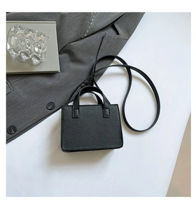 Vue à plat d'un mini sac à main noir grainé avec poignées sur une surface blanche nette