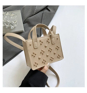 Détail du sac beige en cuir grainé avec rivets décoratifs et finitions élégantes