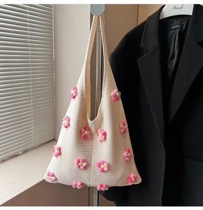 Detail der gestrickten Umhängetasche mit handgefertigten 3D-Häkelblumen in Cremeweiß