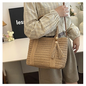 Detail van stro strandtas met decoratieve franjes en houten kraalaccenten voor een retro look