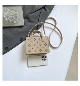 Détail du sac bandoulière beige clouté avec texture grainée et motifs de rivets floraux