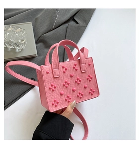 Détail du sac rose en cuir avec rivets décoratifs en forme de fleurs 3D et poignée