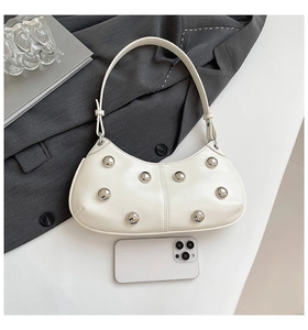 Détail du sac demi-lune en cuir blanc avec rivets et smartphone pour l'échelle