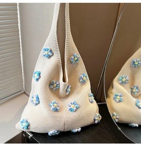 Gros plan détaillé du sac en tricot crème avec des fleurs en crochet violettes et jaunes